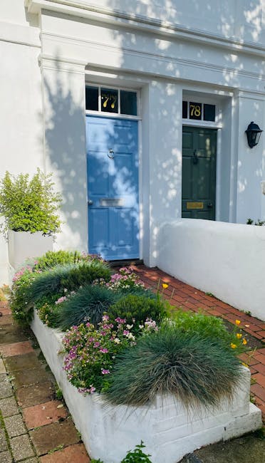 A well-maintained front garden on the St Helier estate featuring neatly trimmed hedges and a variety of lush green plants. The lawn has vibrant, evenly cut grass with a textured surface, bordered by g